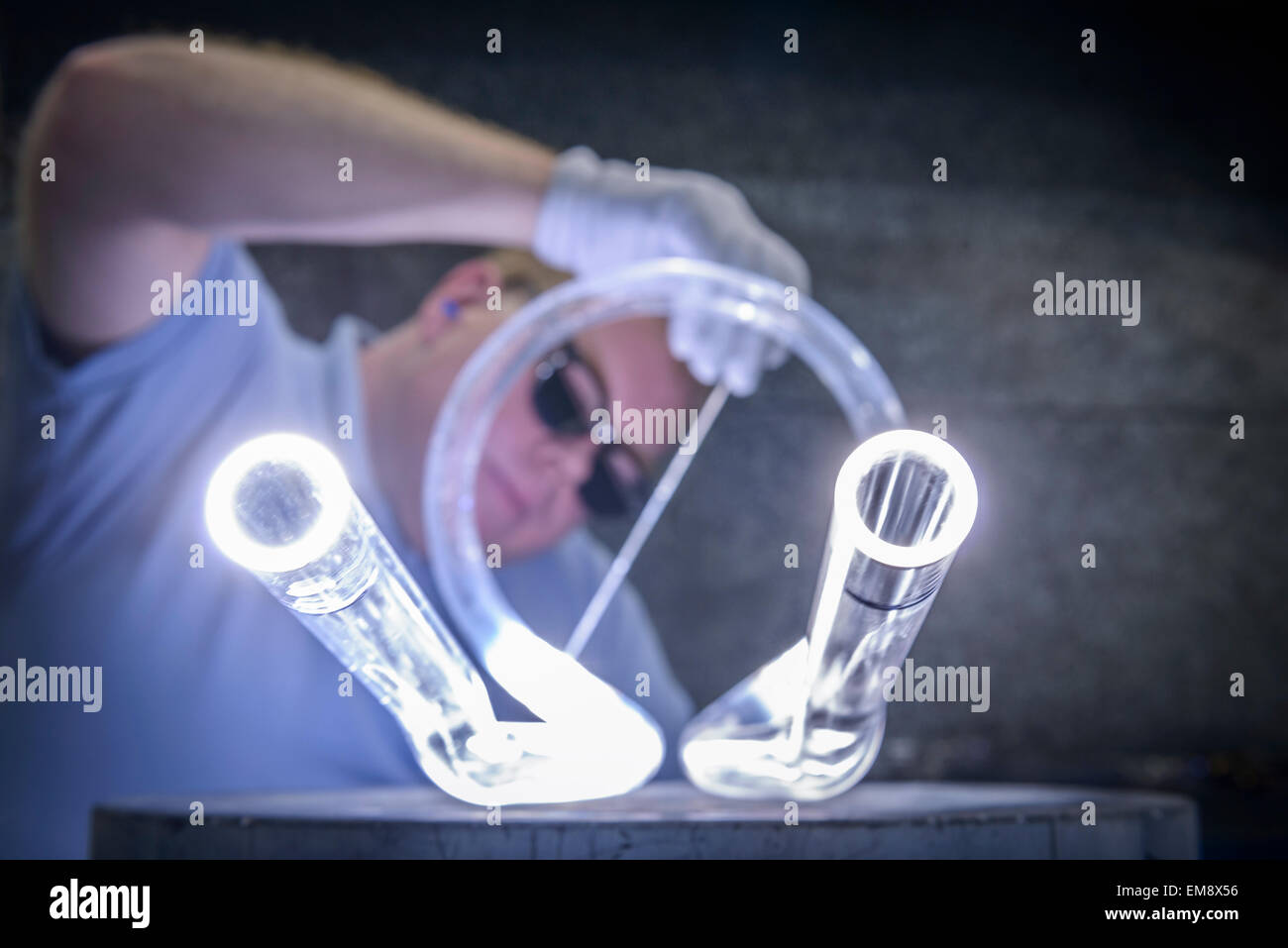 Industrial glass blower welding glass tubes Stock Photo