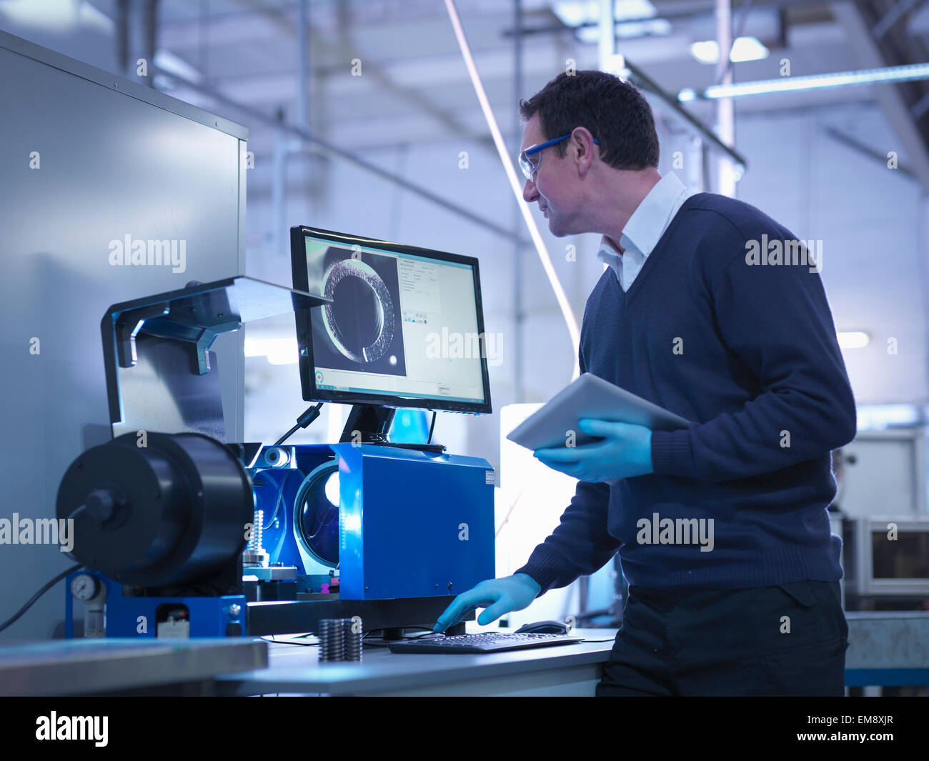 Engineer testing automotive part with digital tablet in factory Stock Photo
