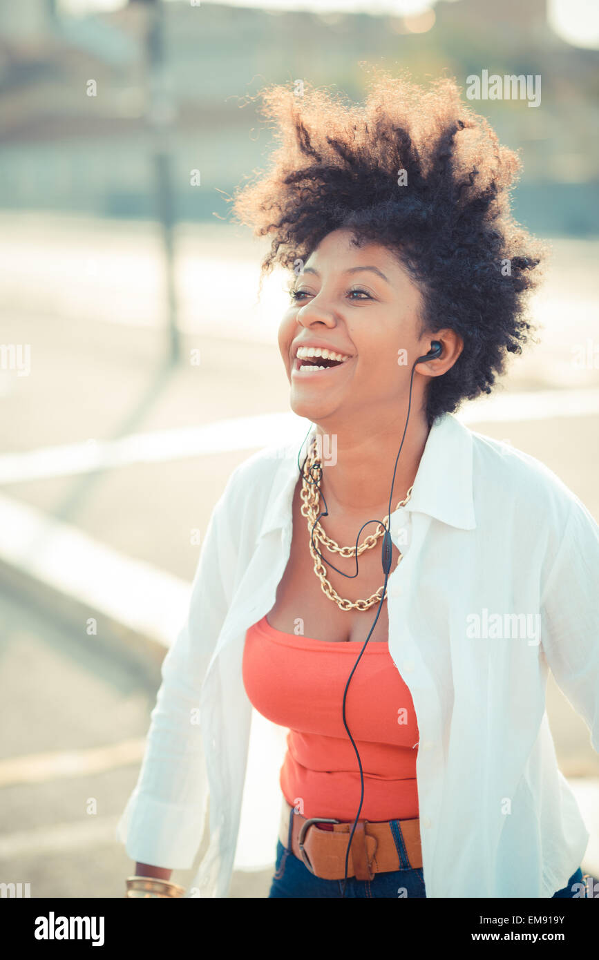Young woman laughing with music on earphones in city Stock Photo