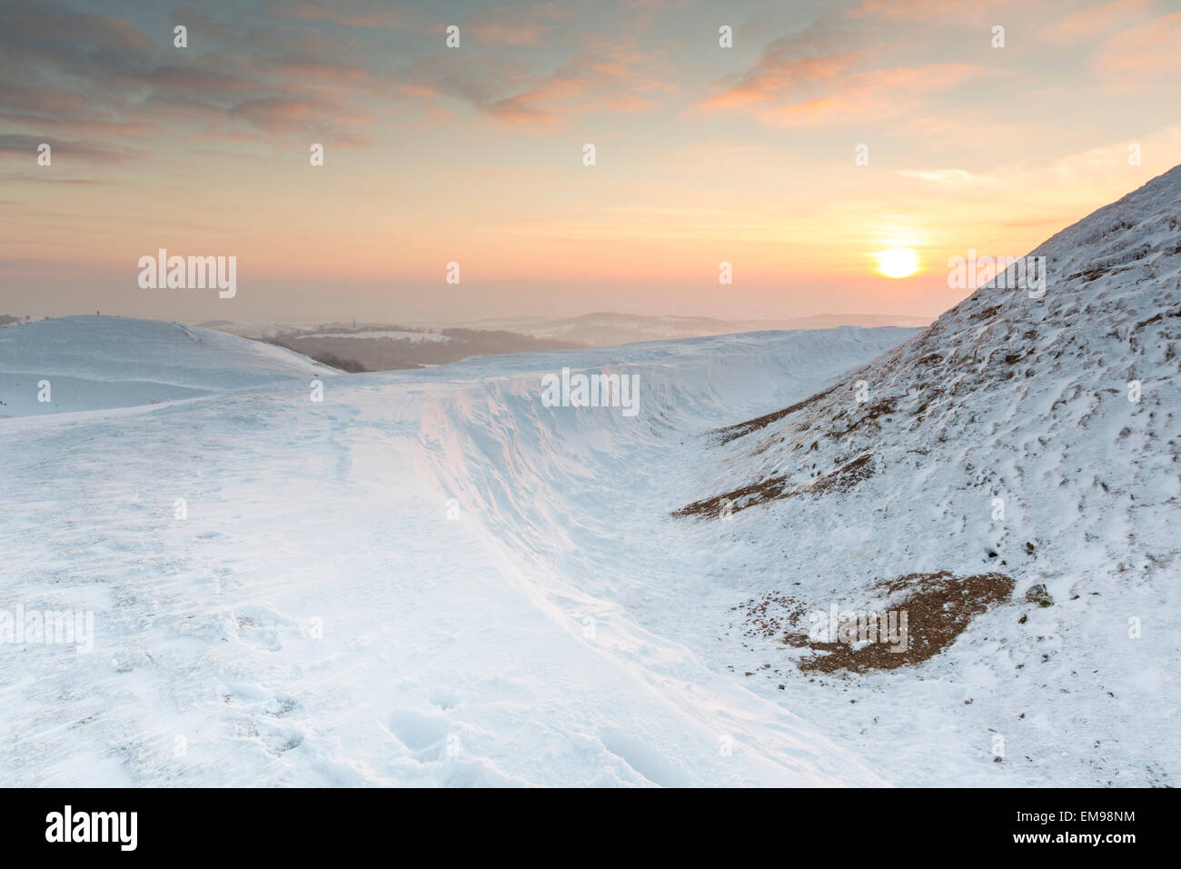 Sun setting behind a snow scene of British Camp Hereford Beacon Malvern