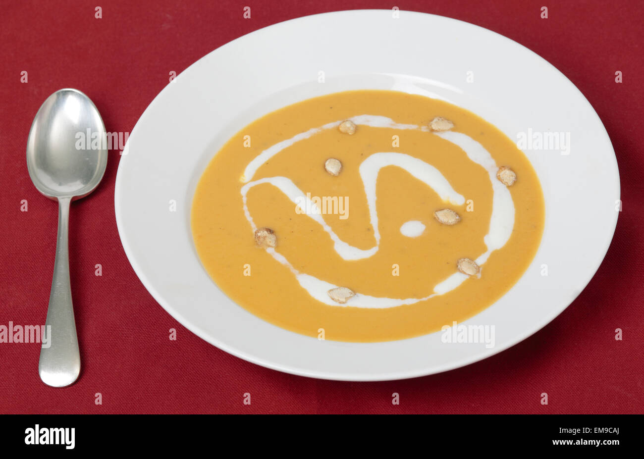 Traditional French butternut squash cream soup with soured cream and toaste squash seed garnish. Stock Photo