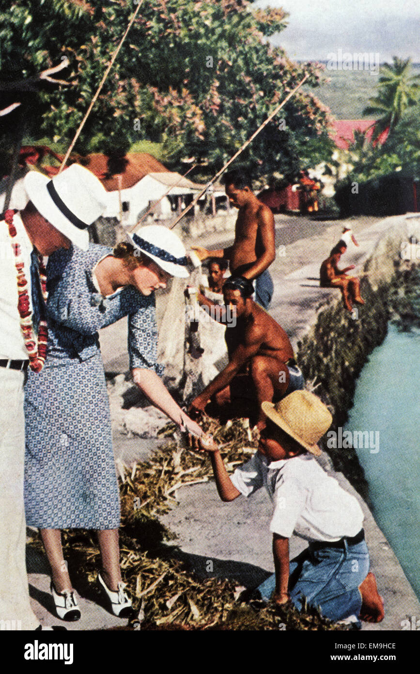 C.1935 Tourist Advertisement, Caucasion Couple Talking To Young Local Boy. Stock Photo