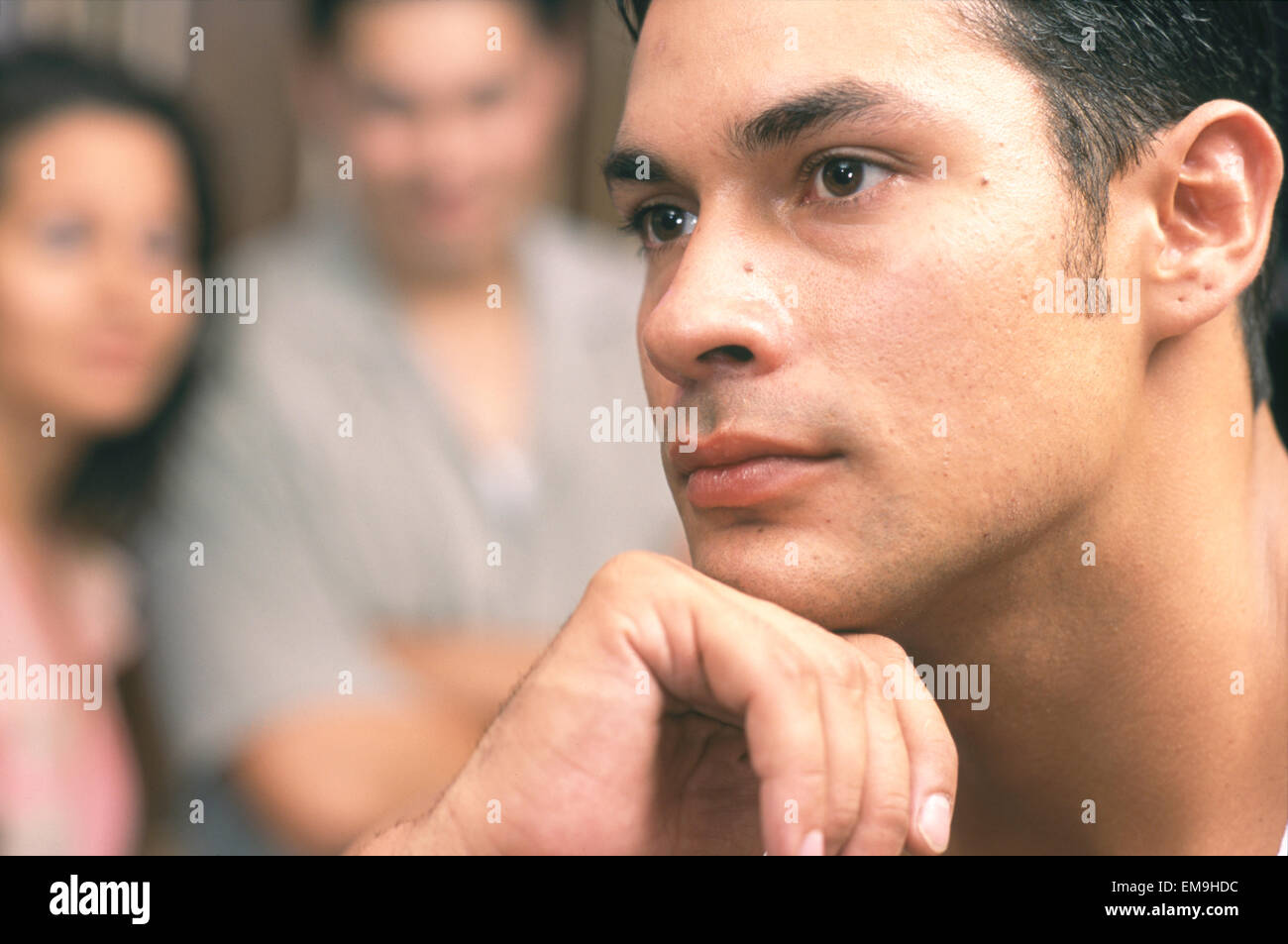 Portrait of contemplative man with couple in background Stock Photo