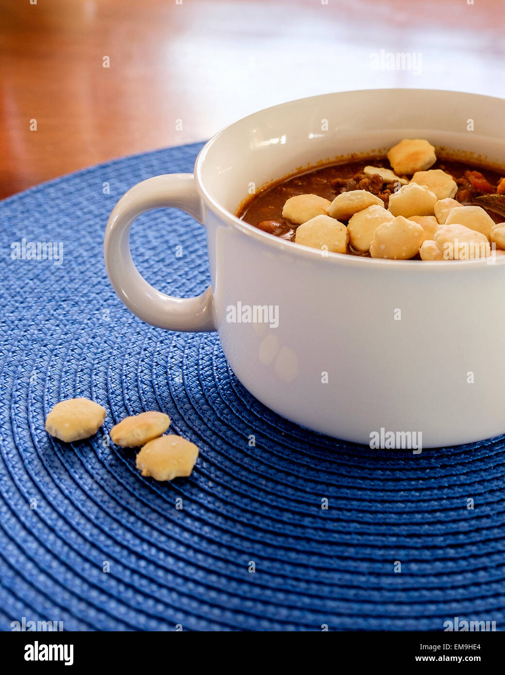 Homemade beef chili with saltines in a white bowl on a blue place mat. USA Stock Photo