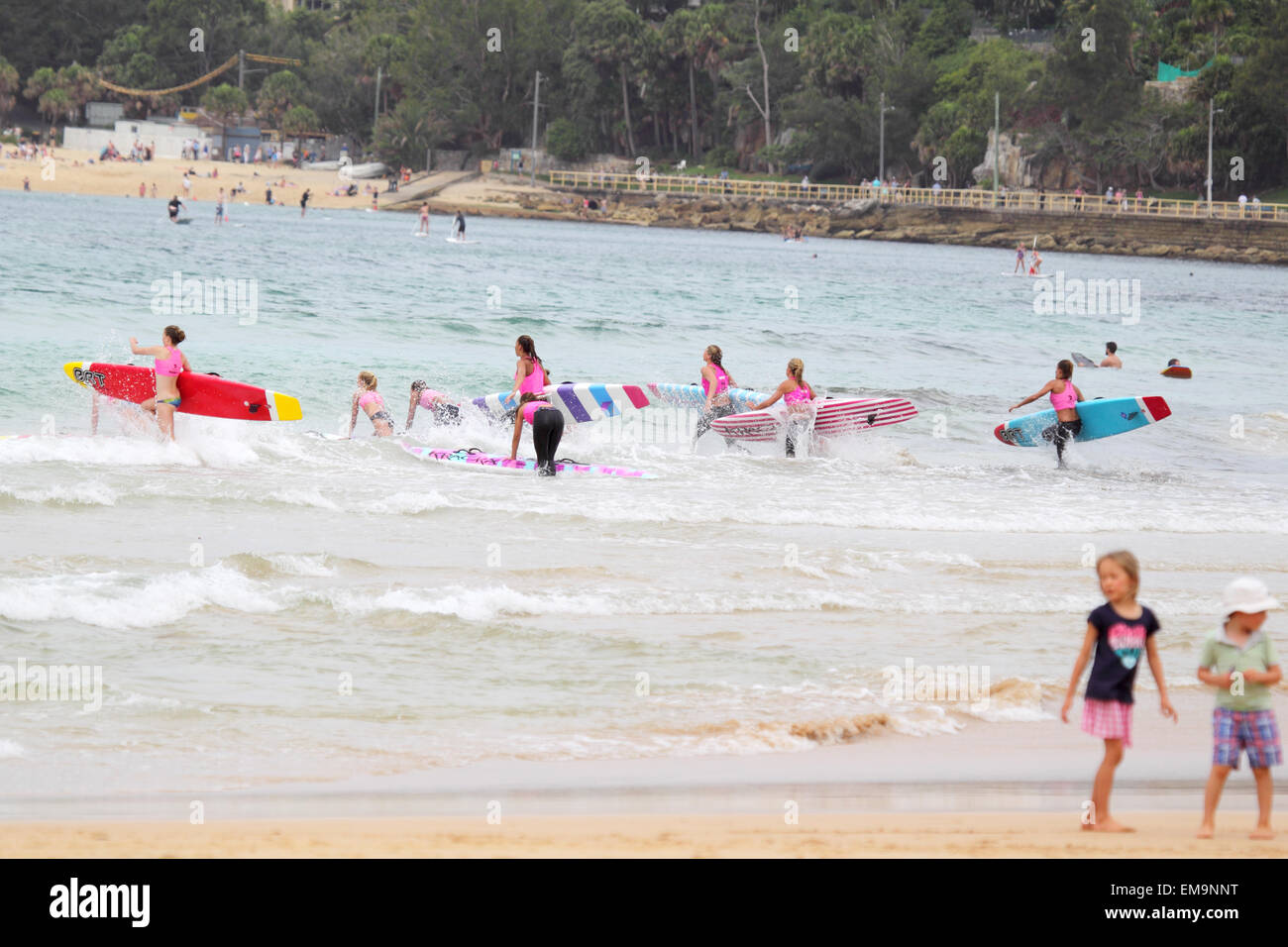Pupils of a Surf School running into the waves with their surfboards at the beach of Manly, Sydney, Australia. Stock Photo