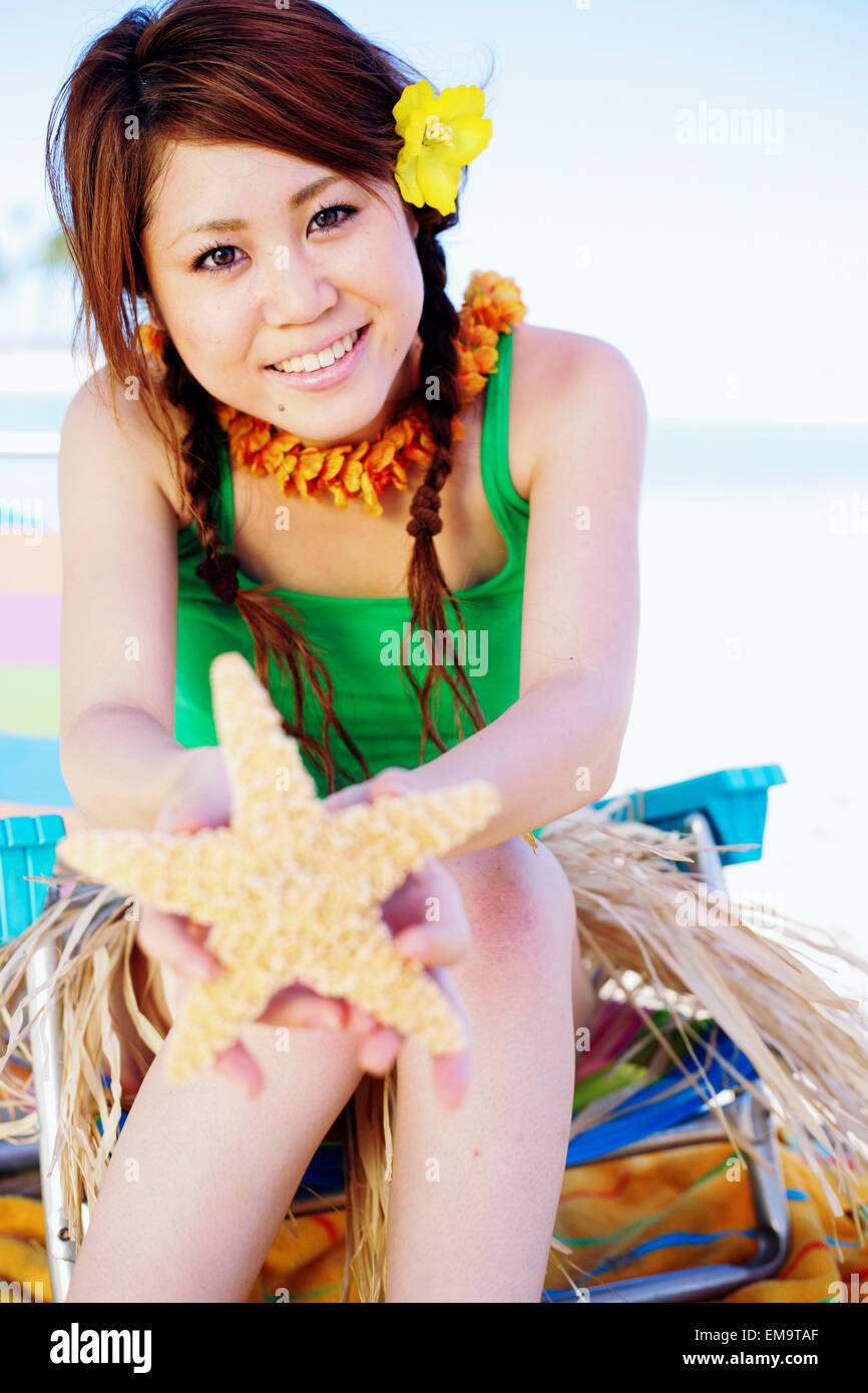 Japanese Girl In Hula Skirt Holding Out A Starfish Stock Photo