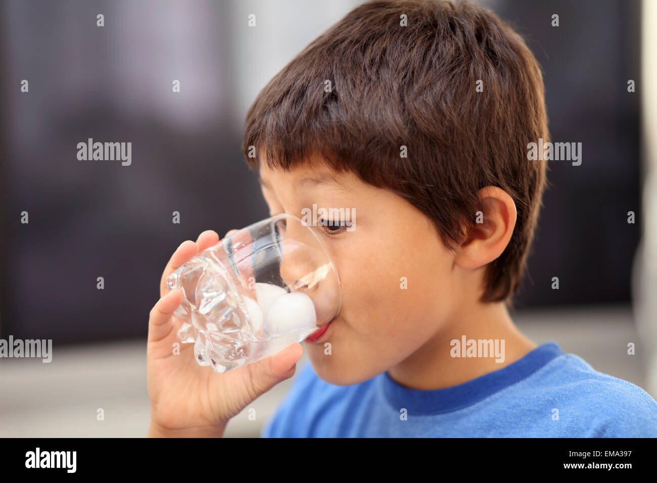 Young boy drinking glass of ice water Stock Photo