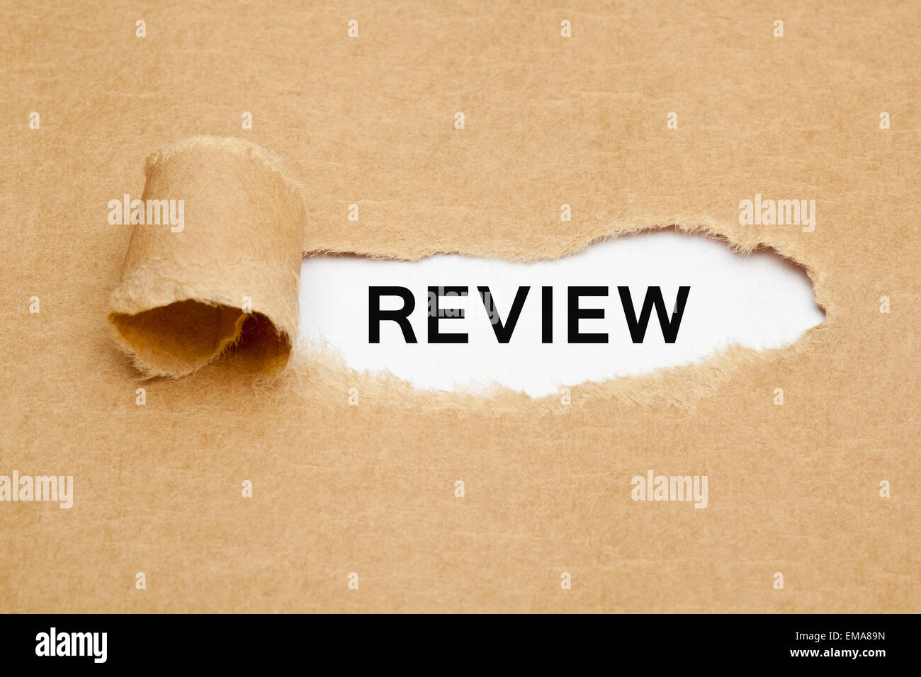 The word Review appearing behind torn brown paper. Stock Photo
