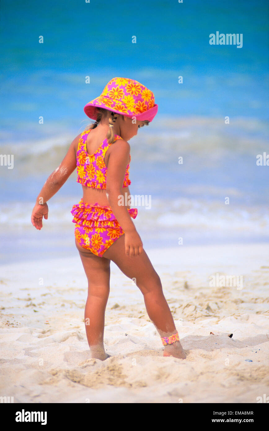 Back Side View Of Little Girl Stepping Carefully In Sand, Matching Outfit Stock Photo