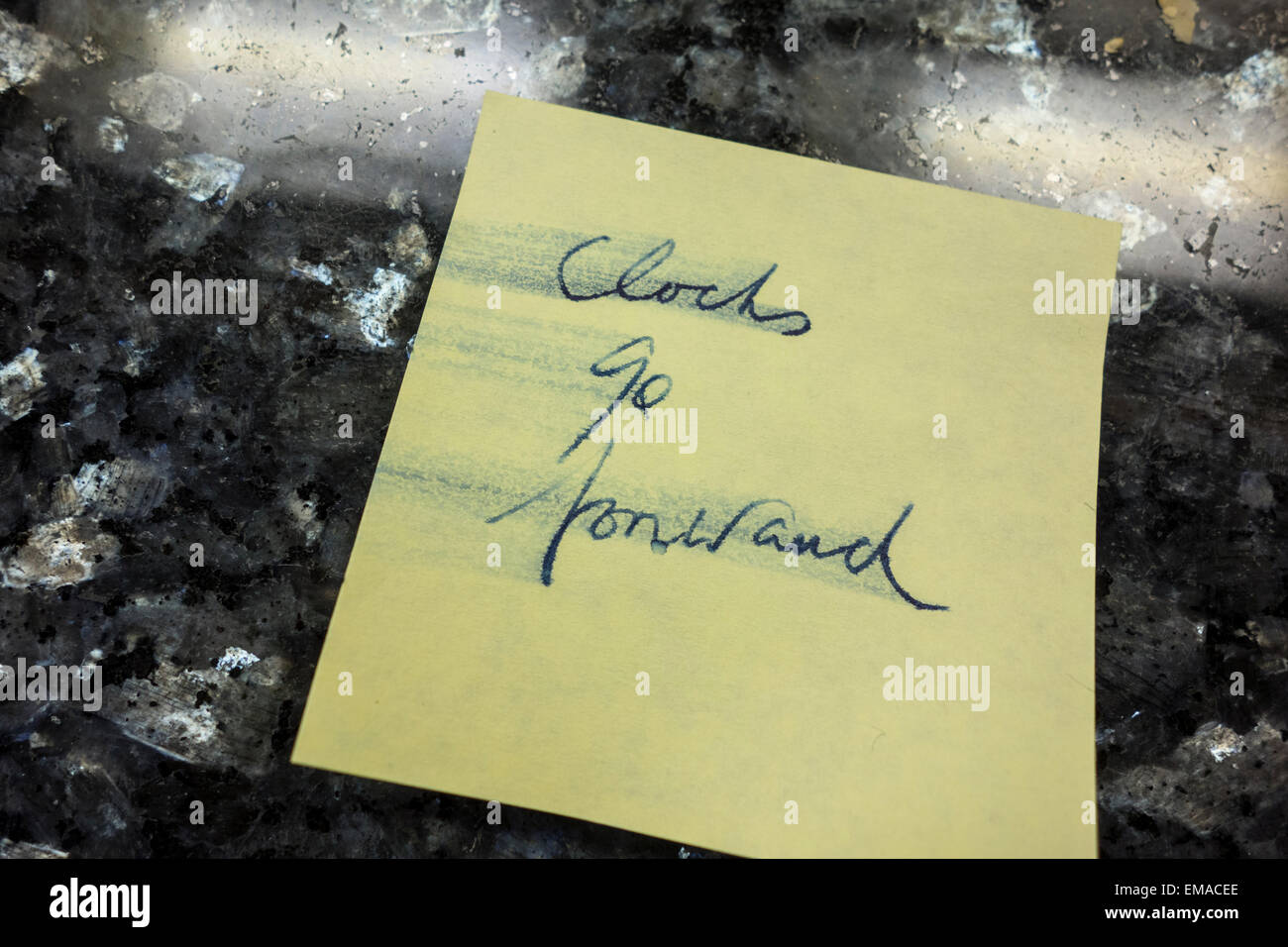 A postit note on a kitchen surface saying "clocks go forward Stock