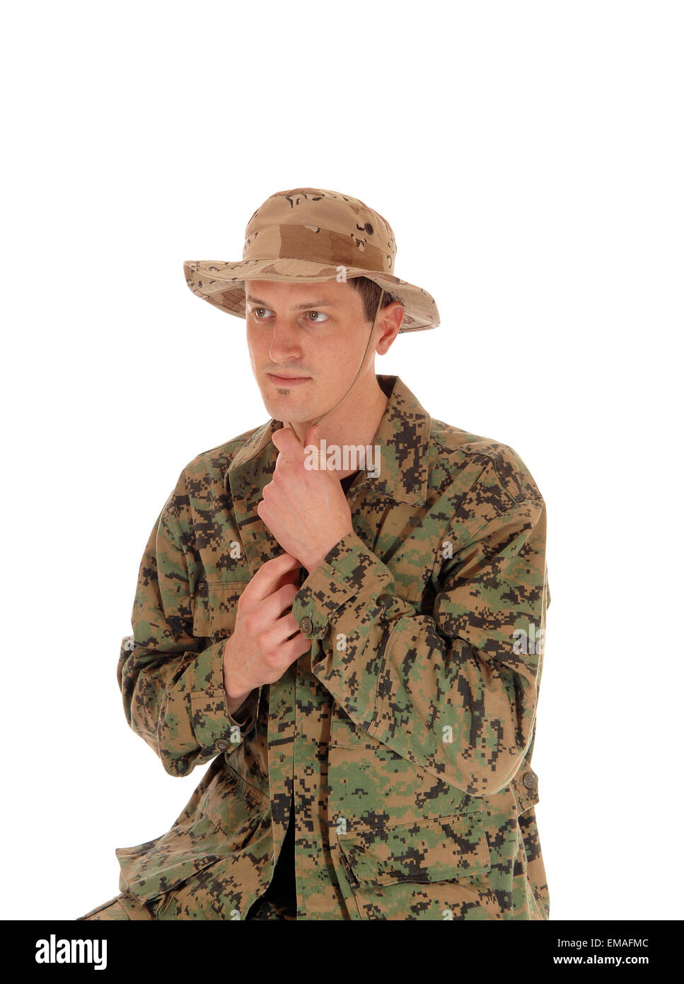 A young soldier sitting for white background in a camouflage uniform and beige hat, isolated for white background. Stock Photo