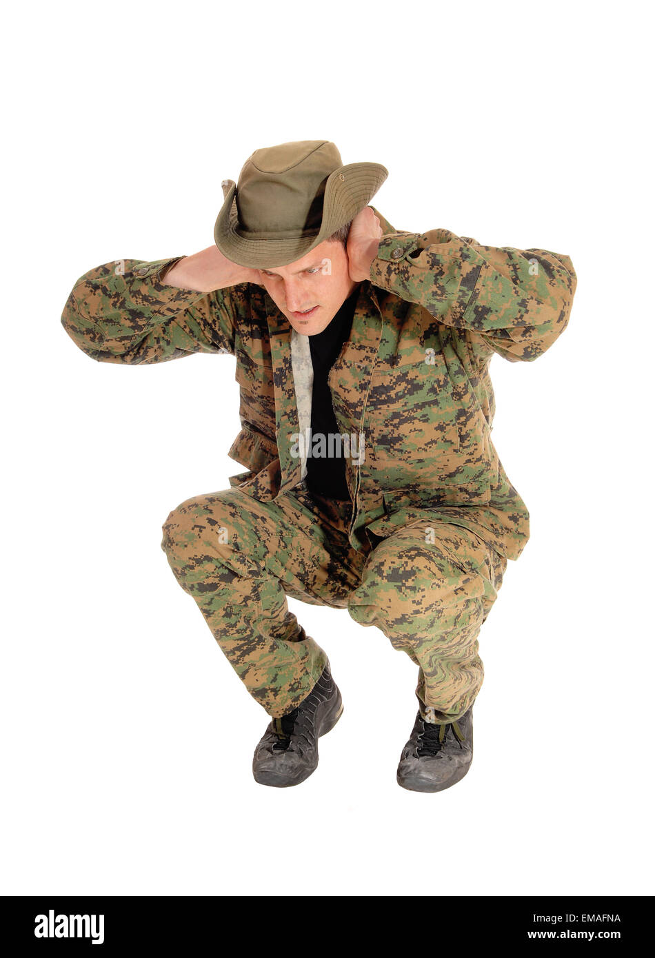 A soldier in camouflage uniform crouching on the floor in anticipation of an explosion, isolated for white background. Stock Photo