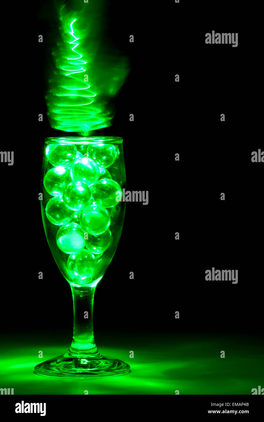 Clear Marbles in a Wine glass with green light painting Stock Photo