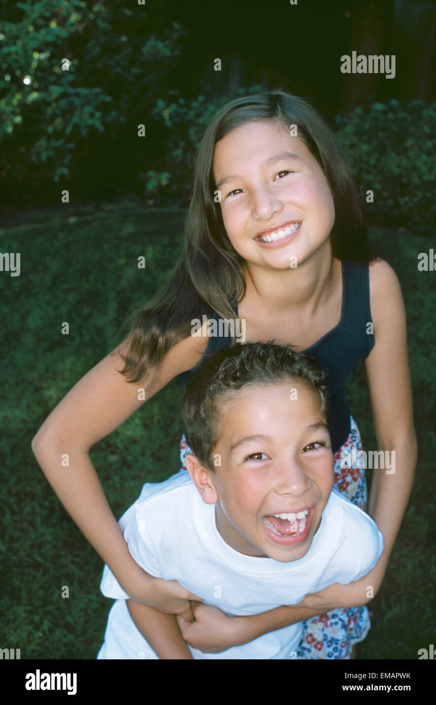 Portrait of happy brother and sister posing in backyard Stock Photo
