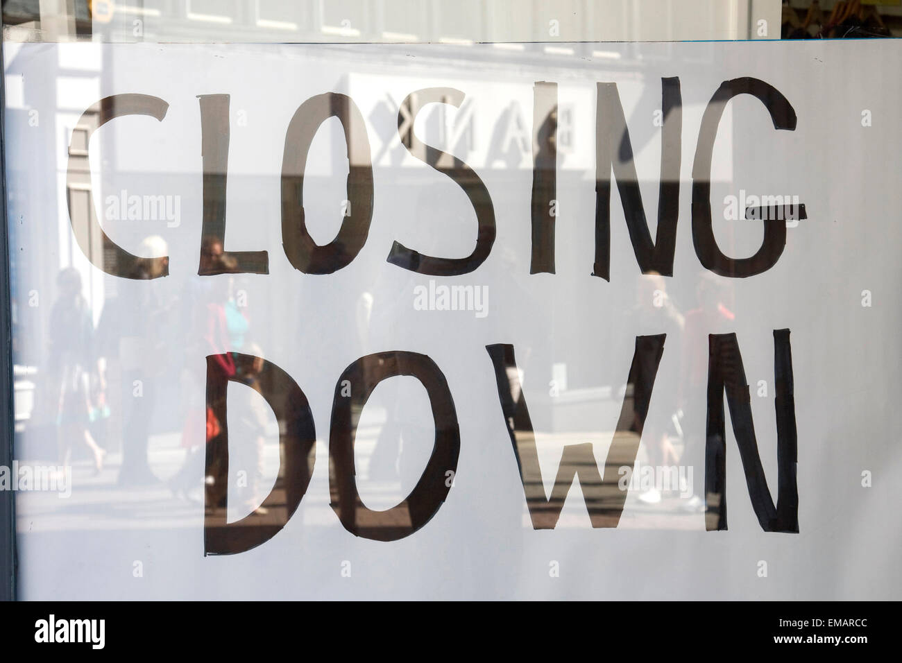 A 'closing down' sign on a High street shop. Shoppers' reflections can be seen along with the recently closed clothing shop BANK. April 18th, 2015. Stock Photo