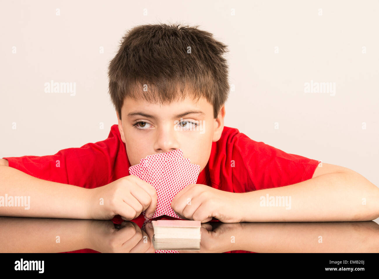Thoughtful young boy playing cards Stock Photo Alamy