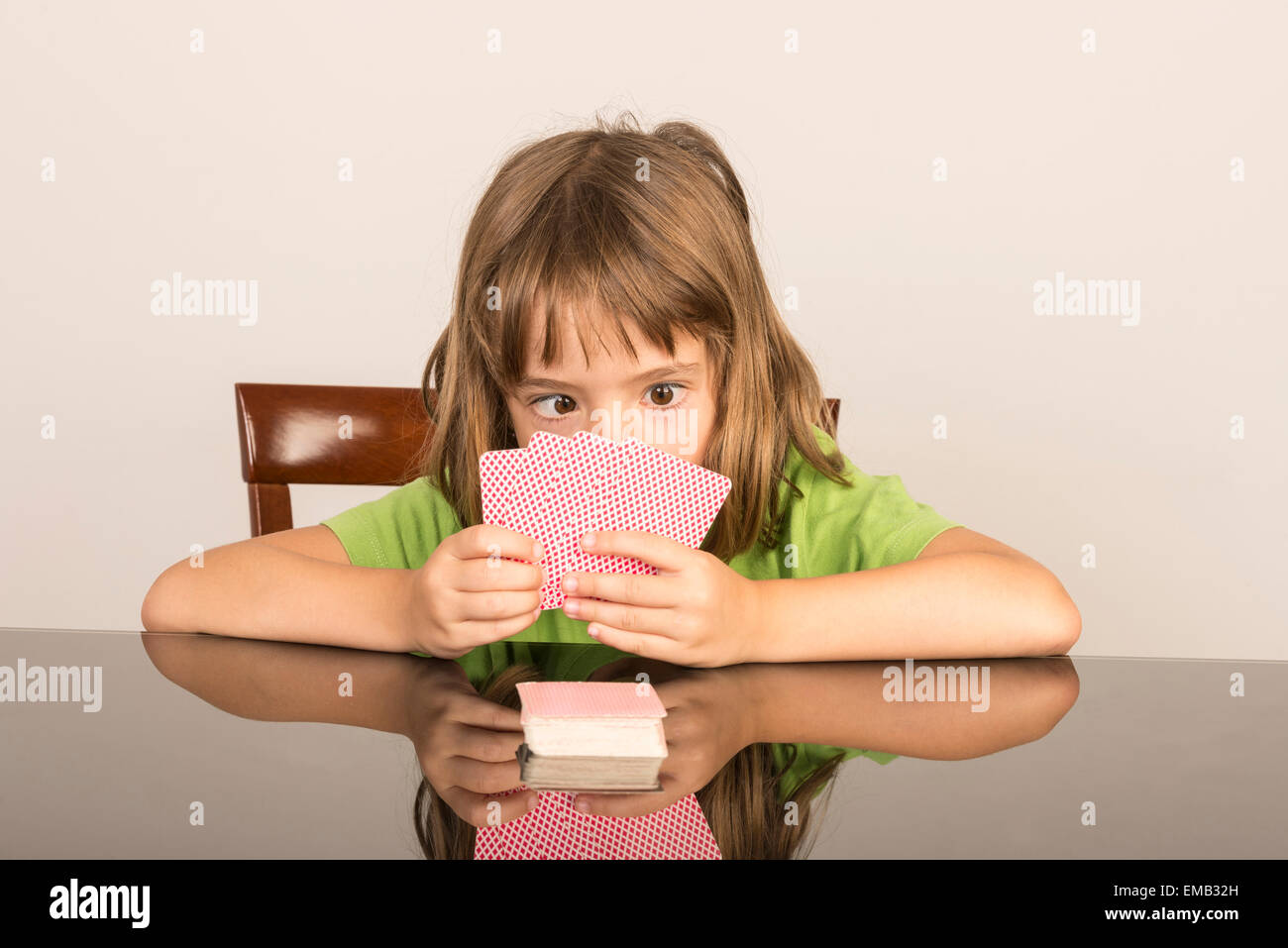 portrait of little girl playing cards with squint Stock Photo