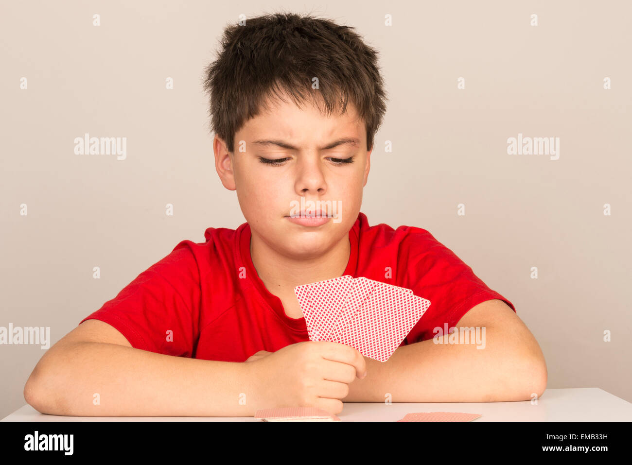 Thoughtful young boy playing cards Stock Photo Alamy