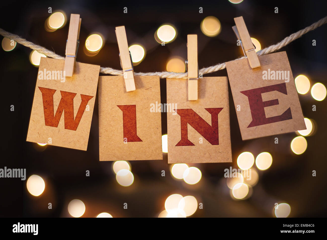 The word WINE printed on clothespin clipped cards in front of defocused glowing lights. Stock Photo
