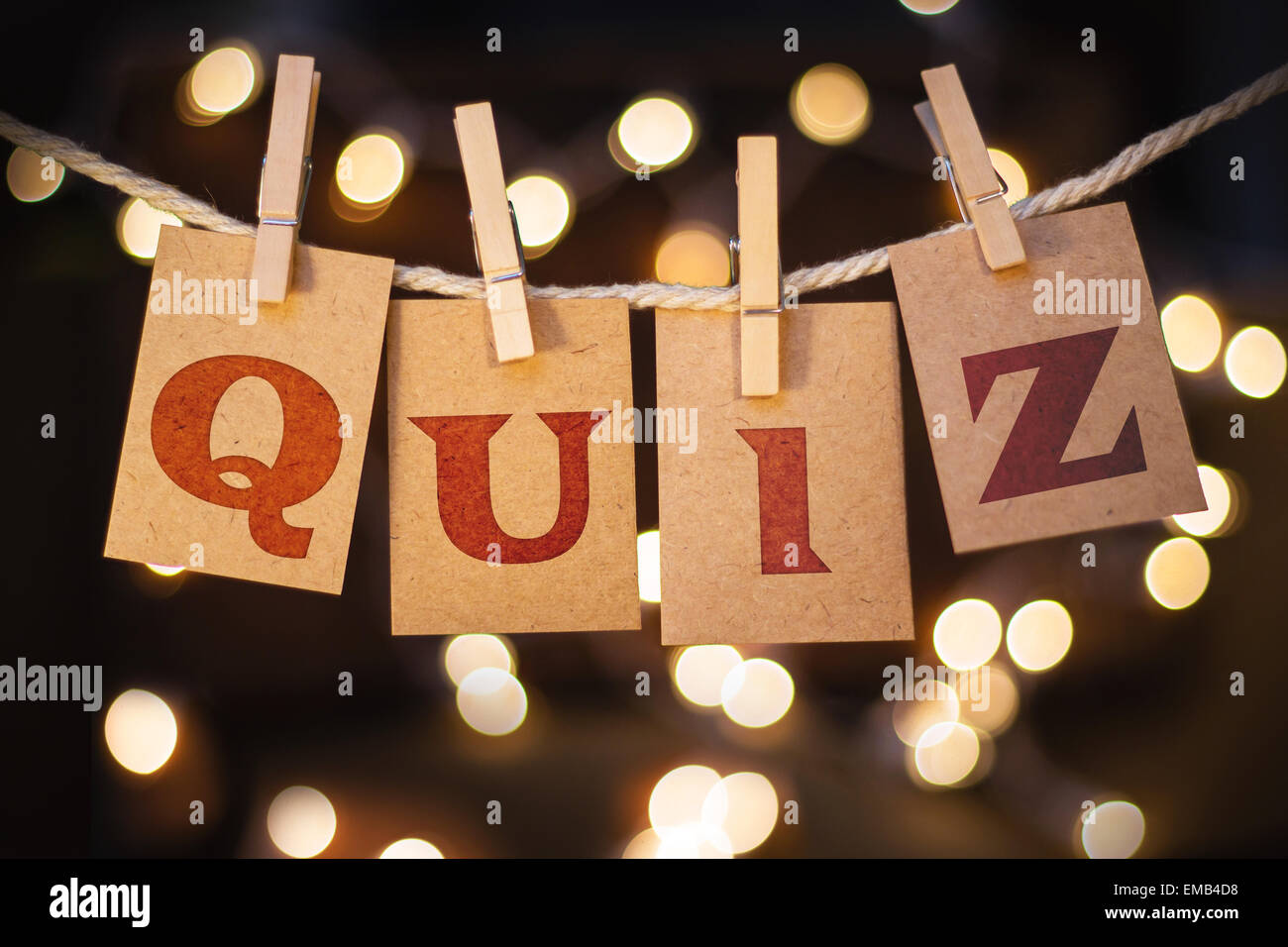 The word QUIZ printed on clothespin clipped cards in front of defocused glowing lights. Stock Photo