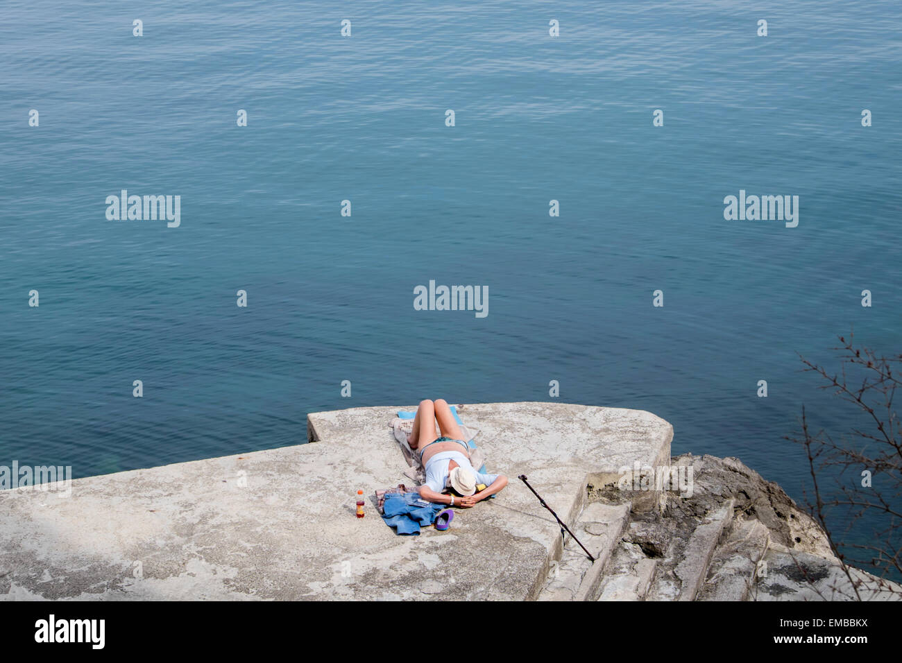 A woman sunbathing on a rocky beach in Opatija, Croatia Stock Photo