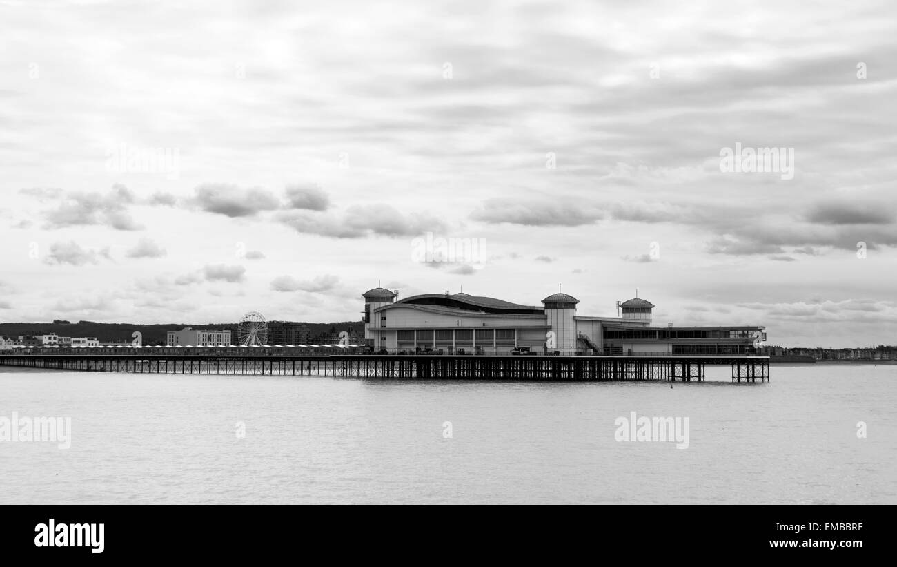 The Grand Pier at Weston-super-Mare at high tide in black and white with a few fluffy clouds in the sky above it. Stock Photo