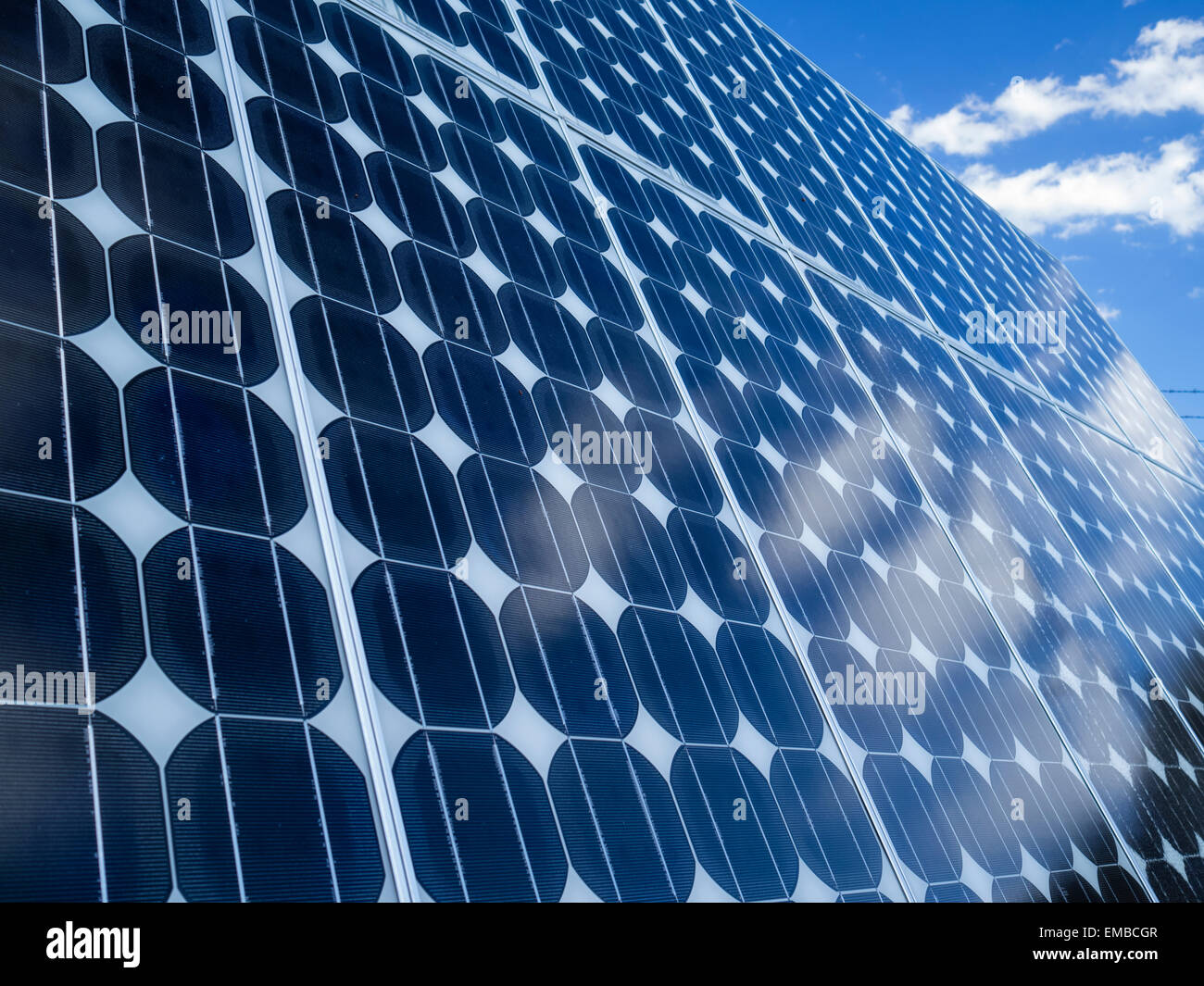 Photovoltaic cell array blue sky with reflections of clouds in solar panels emphasizing environmentally friendly aspect of green renewable energy Stock Photo