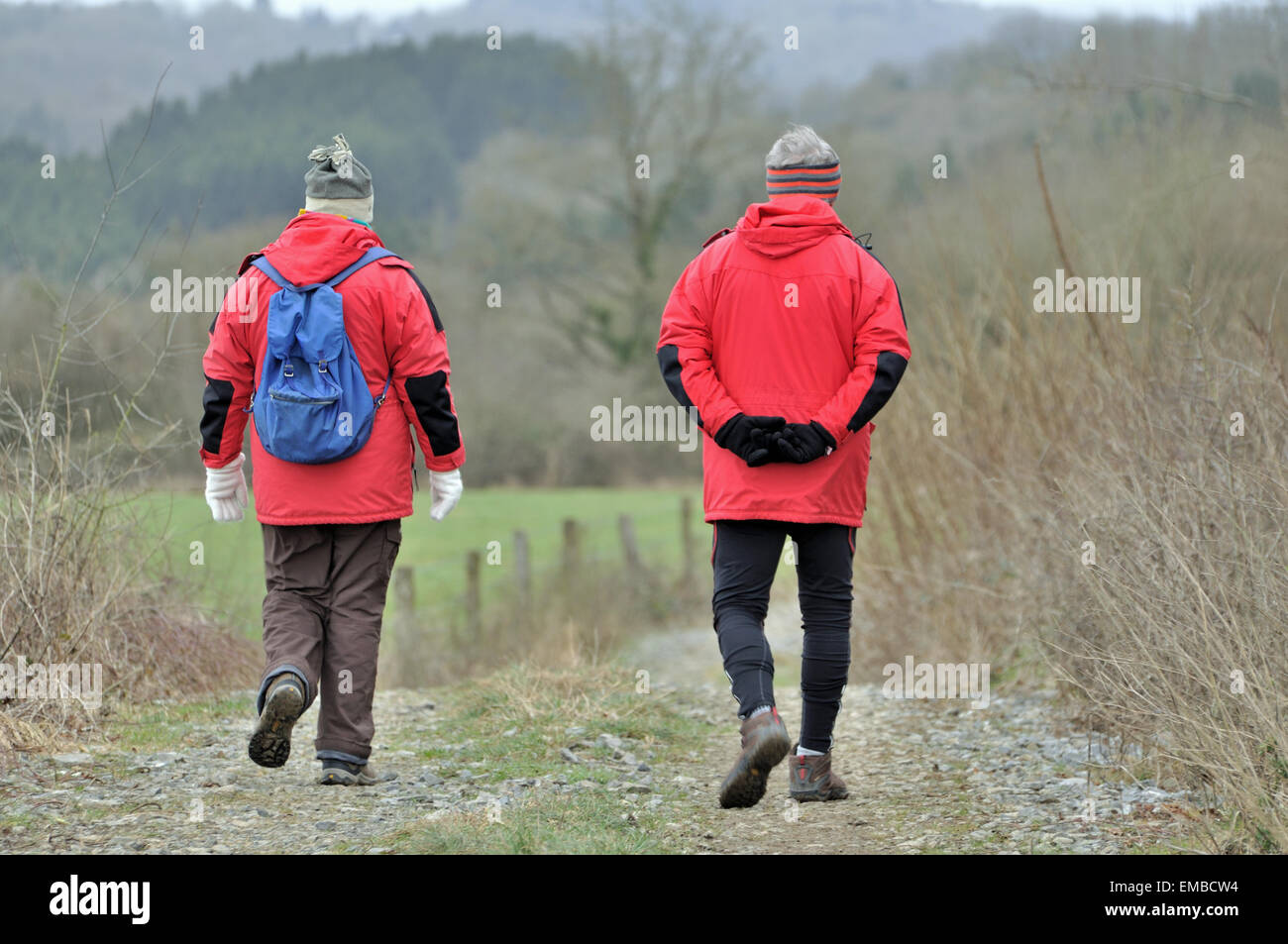 Old wise couple walking and hiking in the country on a footpath during winter. These walkers are enjoying sports outside. Stock Photo