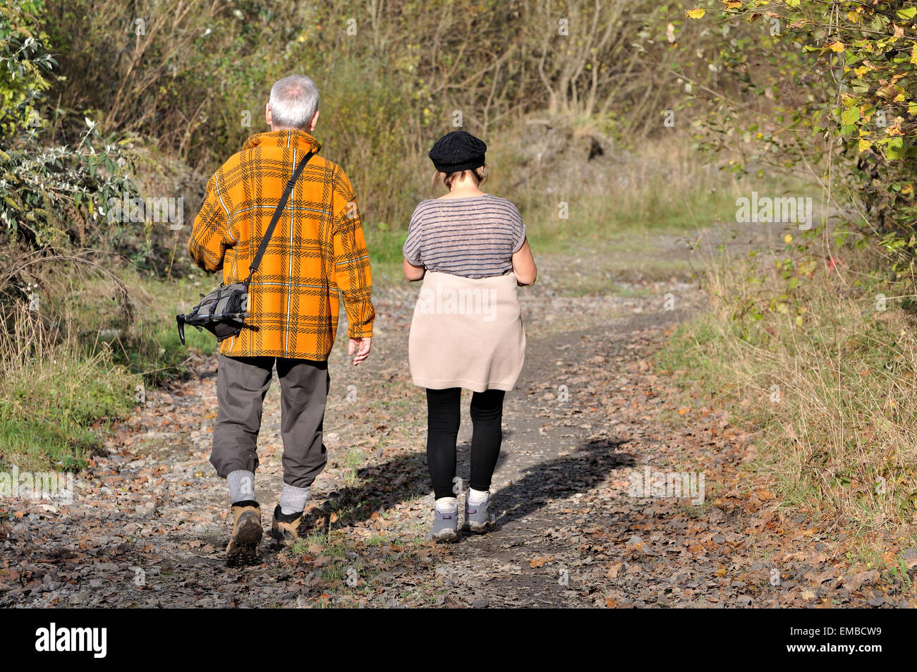 Old wise couple walking and hiking in the country on a footpath during autumn. These walkers are enjoying sports outside. Stock Photo