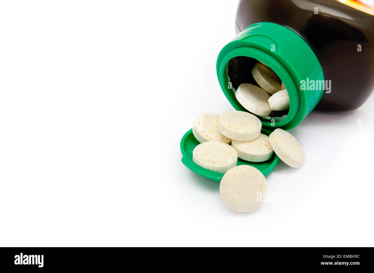 Big white pills spilling out of a green bottle Stock Photo