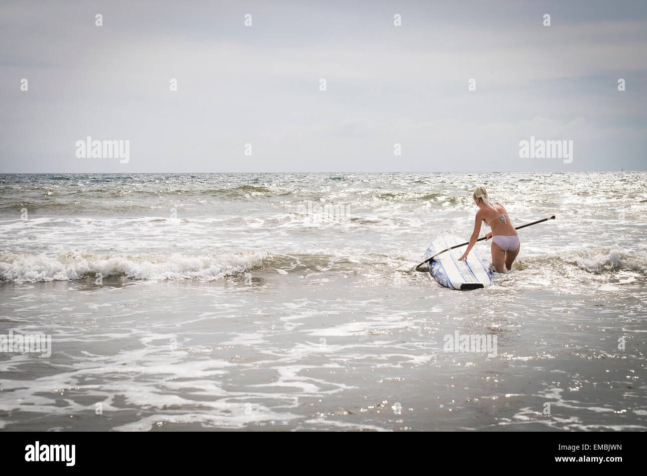 Young woman in the surf of a beach with paddle board, Riviera Nayarit, Pacific Coast, Mexico Stock Photo