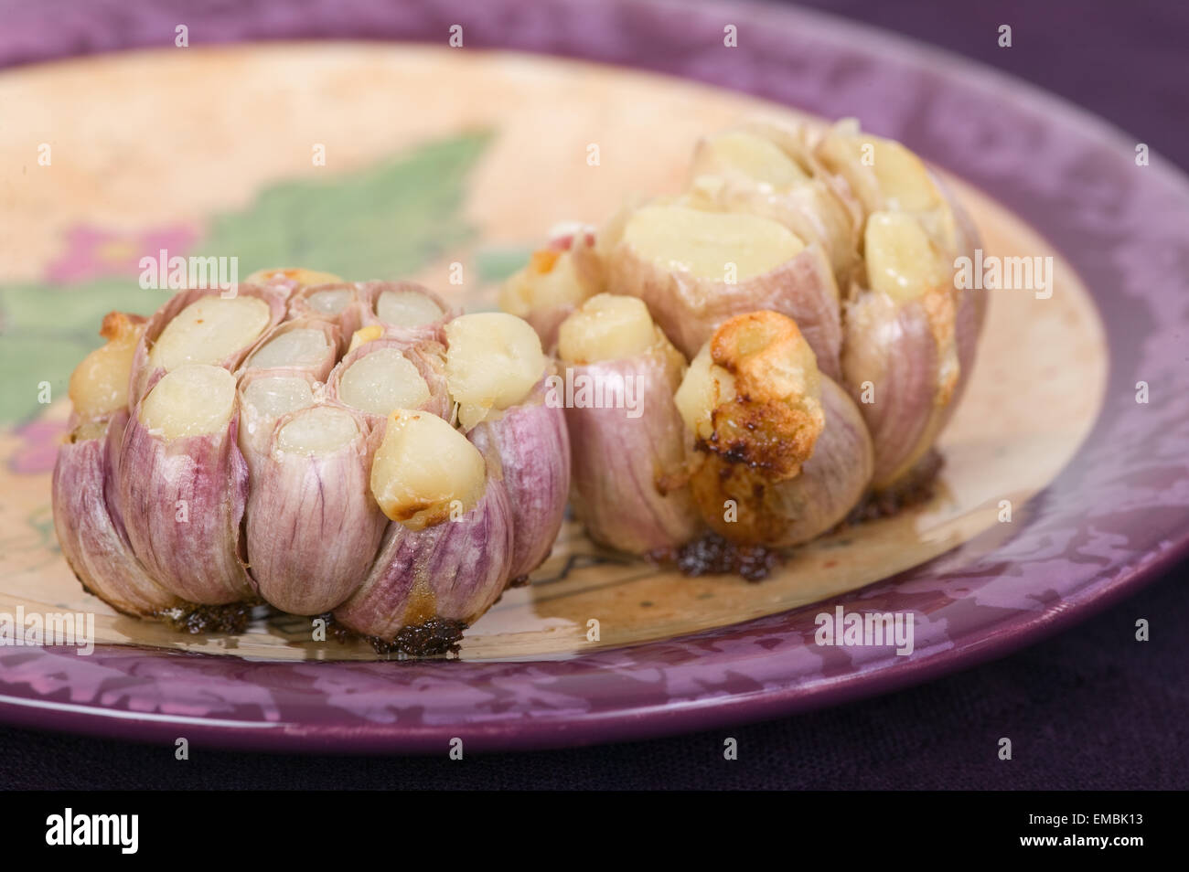 Two roasted Purple Stripe garlic bulbs, showing the individual cloves