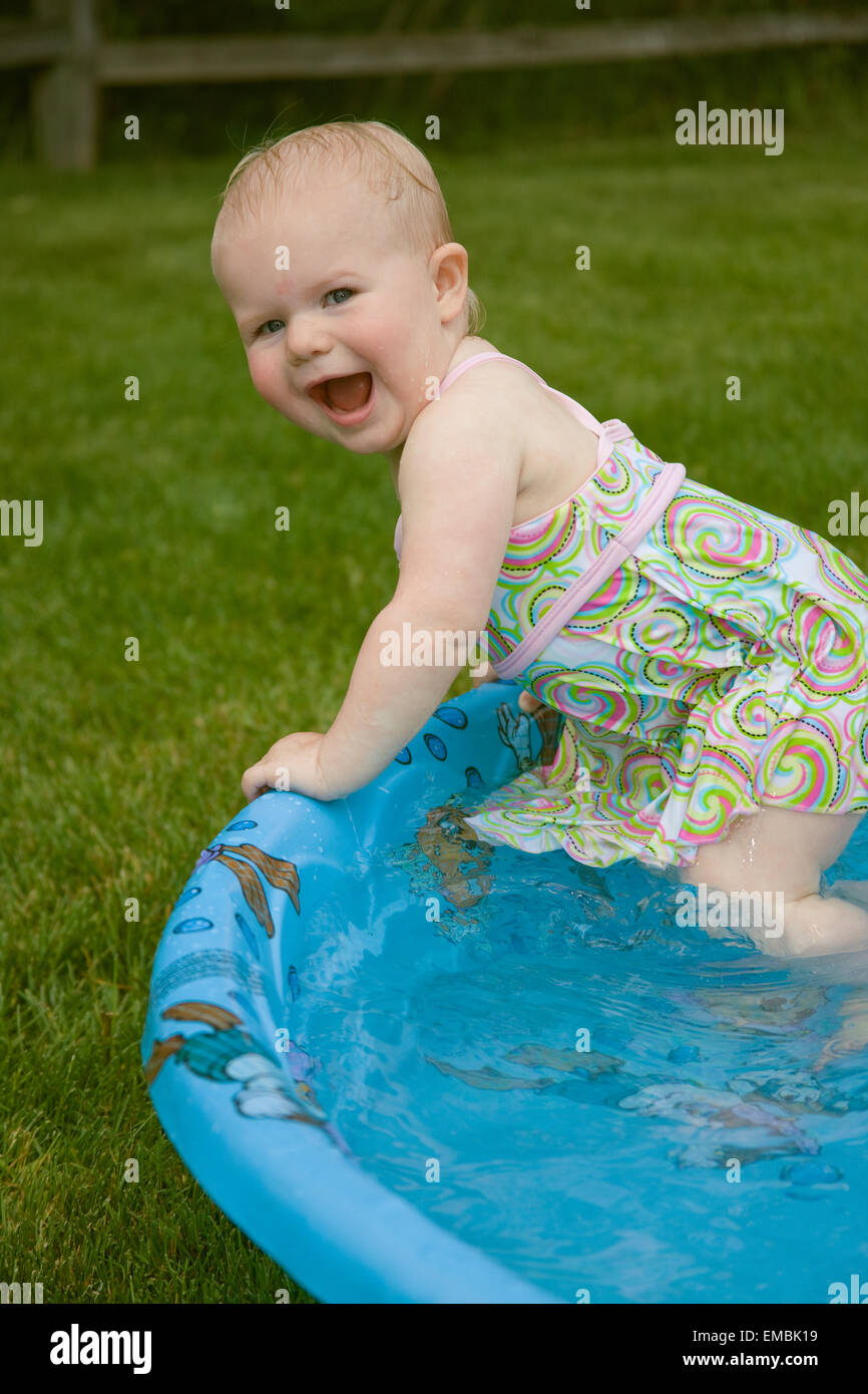 One year old playing excitedly in a wading pool on a hot summer day in