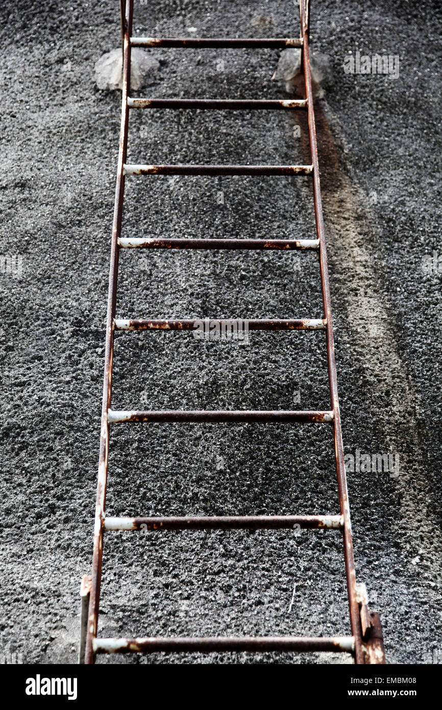 It's a photo of a rusted ladder in steel against a cement wall. It's symmetrical. there is nobody. Stock Photo