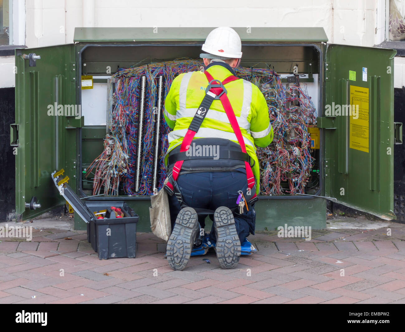 A BT Openreach telecommunications technician working on an equipment cabinet at roadside Stock Photo