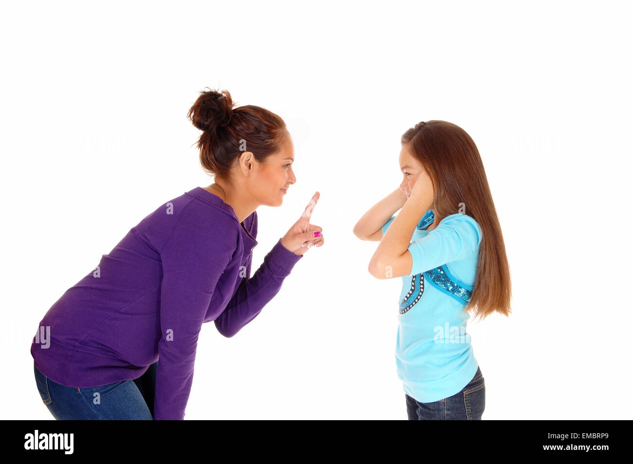 A mother is disciplining her young daughter and the girl holding her ears closed, isolated for white background. Stock Photo