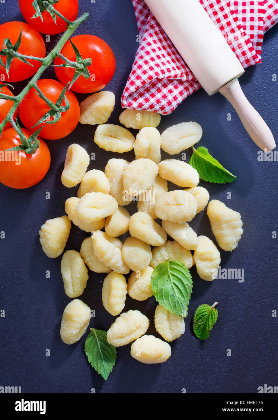 raw gnocchi and basil leaves on black table Stock Photo