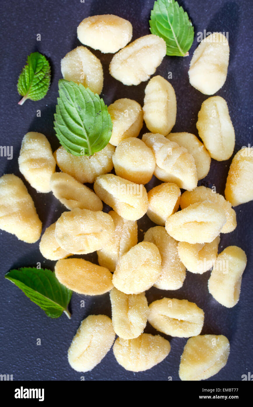 raw gnocchi and basil leaves on black table Stock Photo