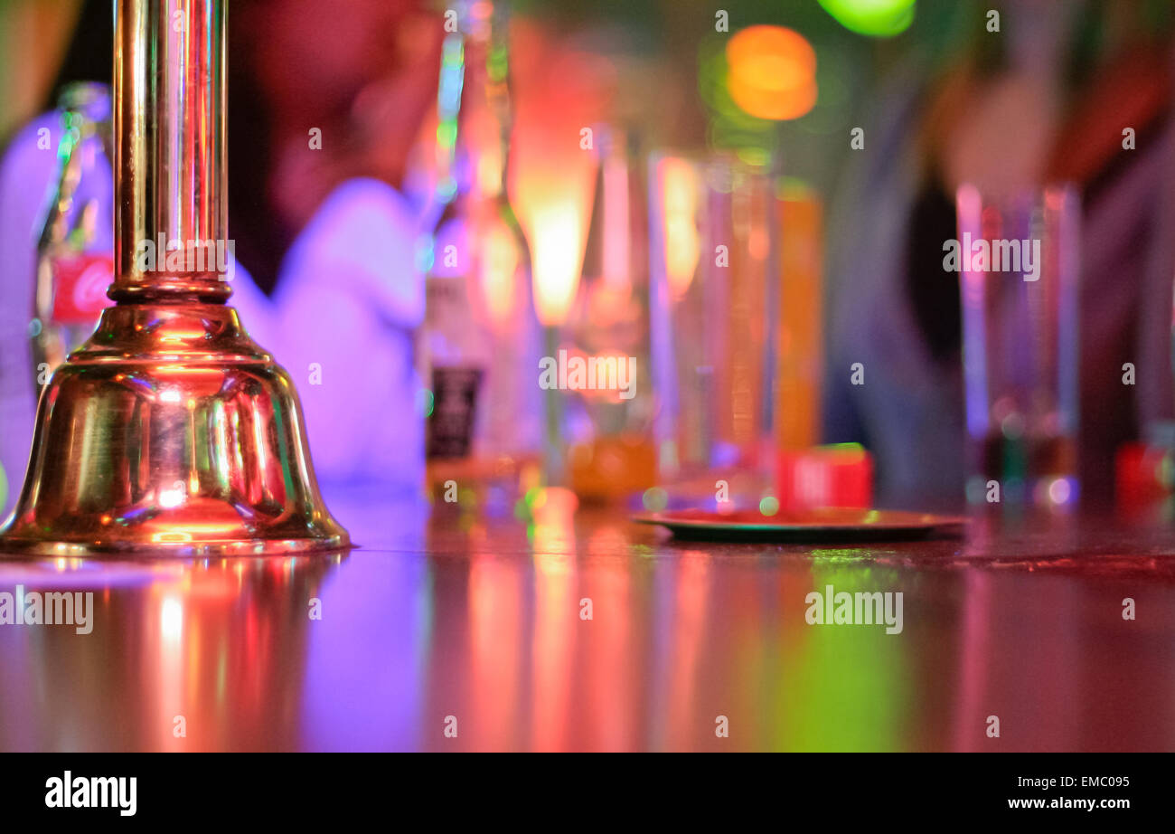 Golden metallic bell over a counter bar with bottles and glasses Stock Photo