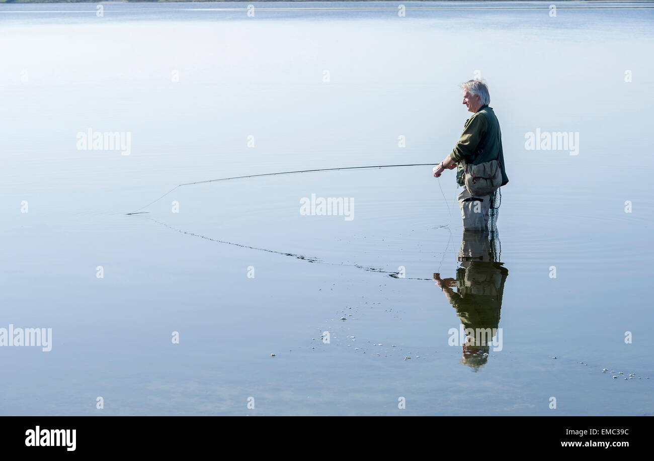 A man fly fishing for trout on a lake at Colliford reservoir on Bodmin