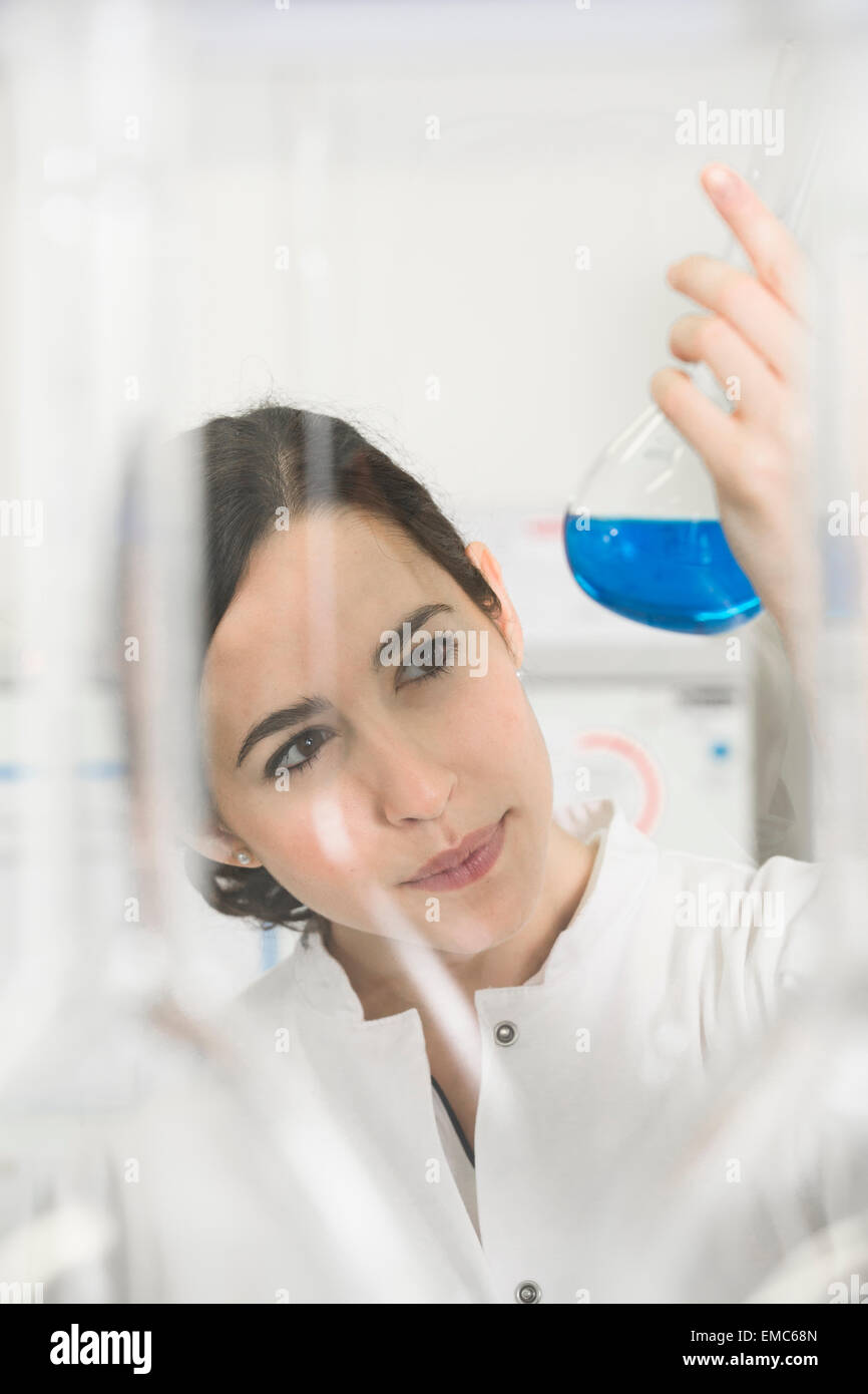 Young scientist in laboratory judging blue liquid in flask Stock Photo ...