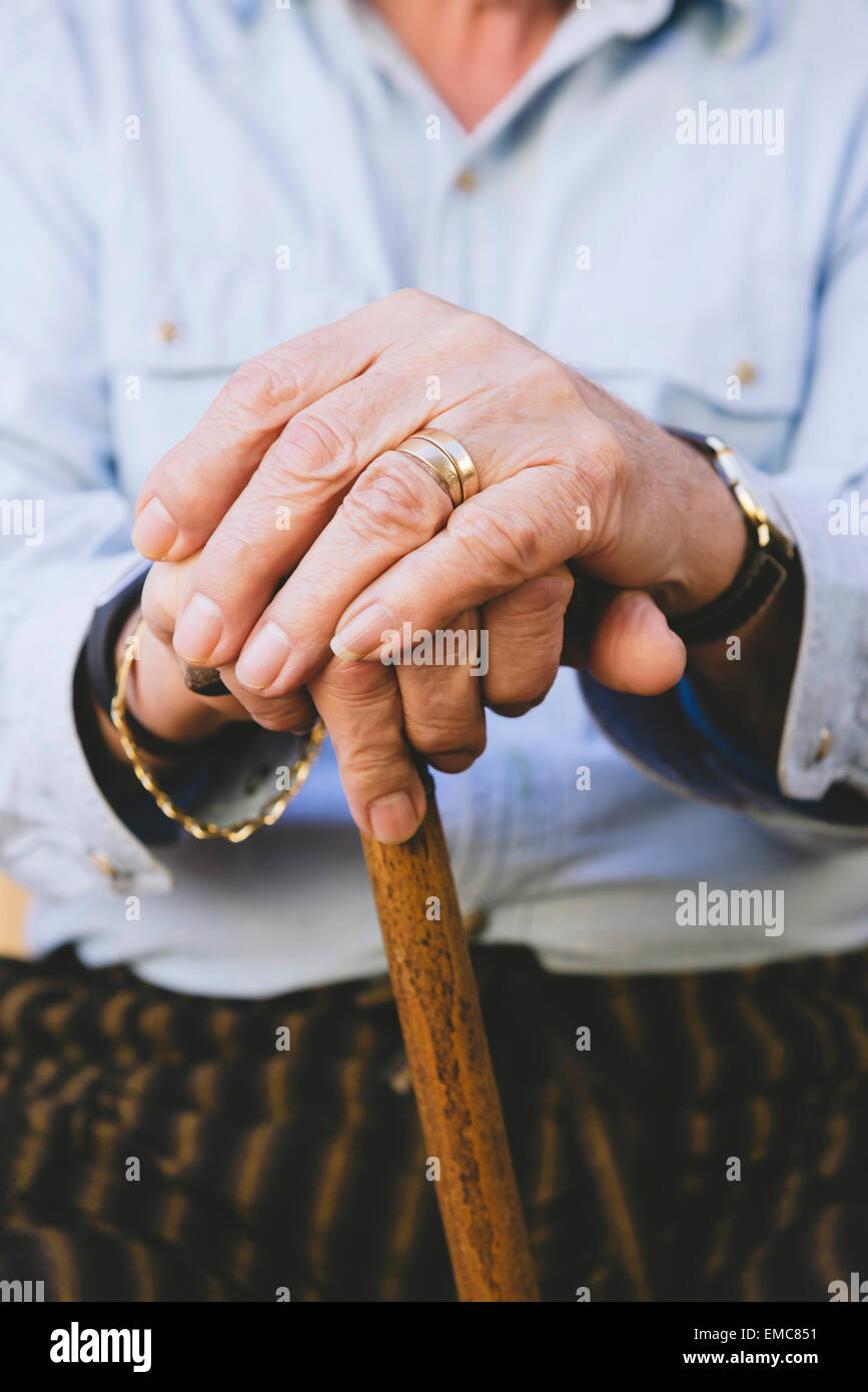 Close-up of old man's hands resting on a cane Stock Photo