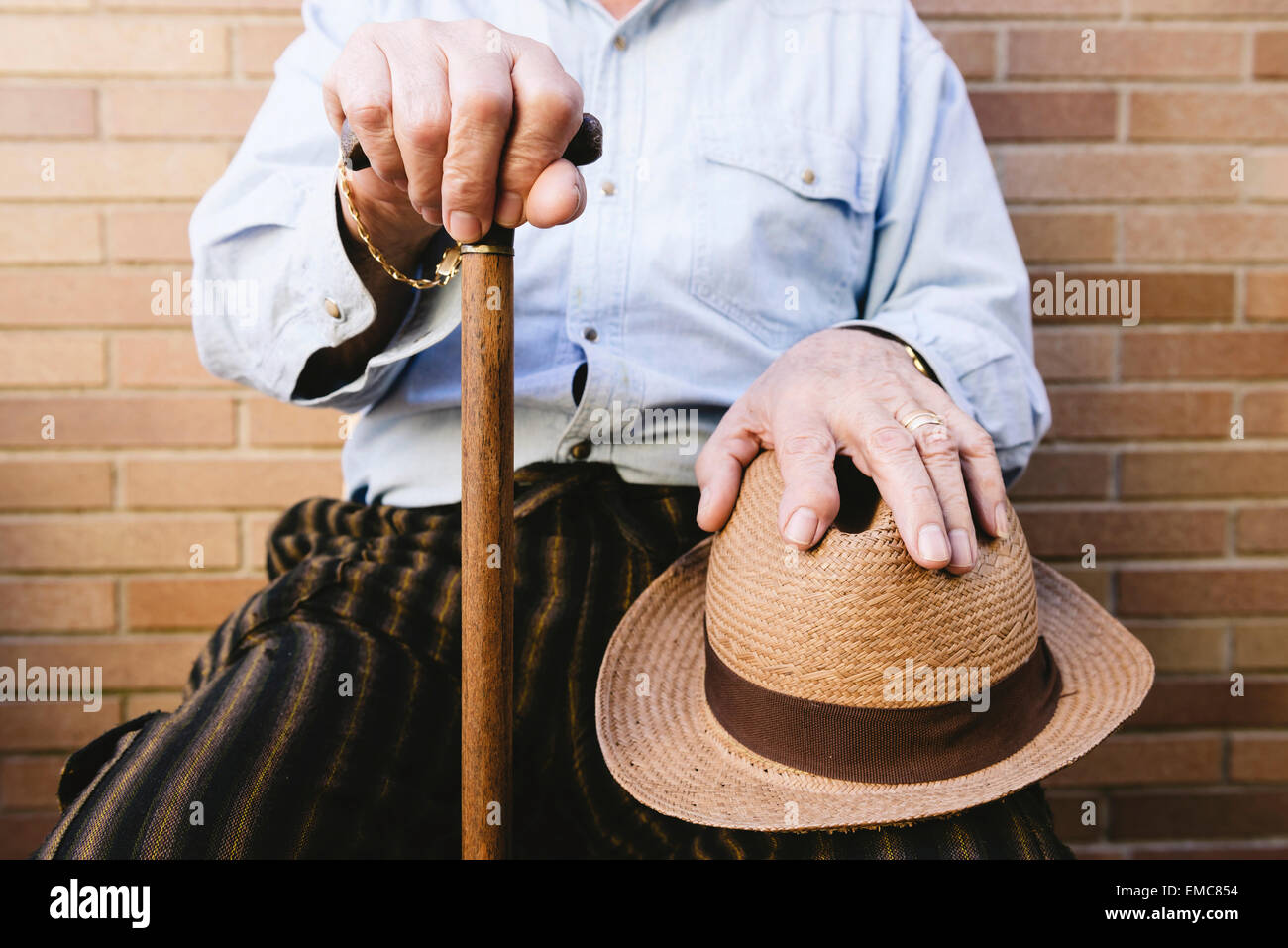 Close-up of old man with cane and straw hat Stock Photo