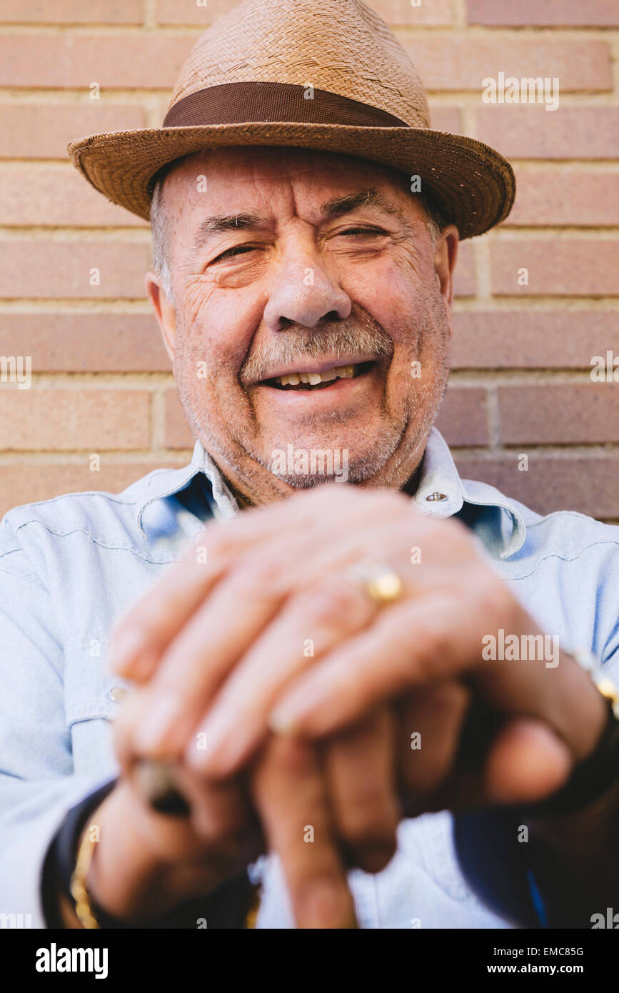 Smiling old man with hat resting on cane Stock Photo