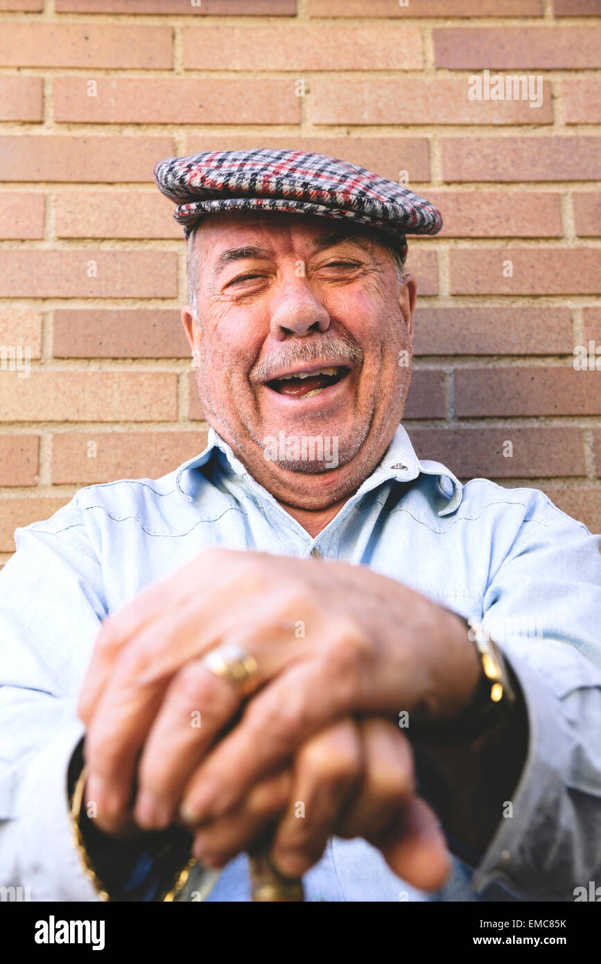 Laughing old man with beret resting on cane Stock Photo