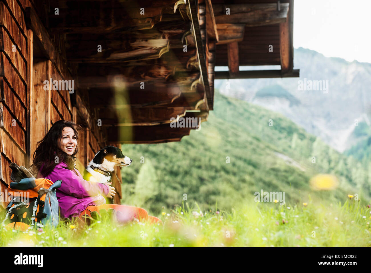 Austria, Altenmarkt-Zauchensee, young woman and dog in front of an Alpin cabin Stock Photo