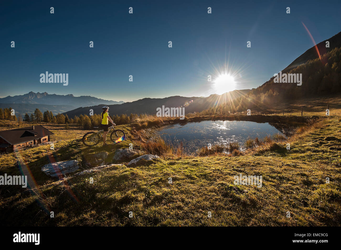 Austria, Altenmarkt-Zauchensee, young woman with mountain bike in the mountains at sunrise Stock Photo