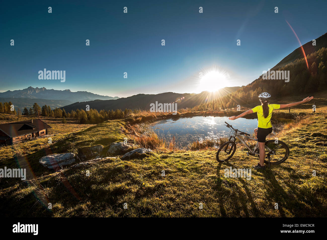 Austria, Altenmarkt-Zauchensee, young woman with mountain bike in the mountains at sunrise Stock Photo