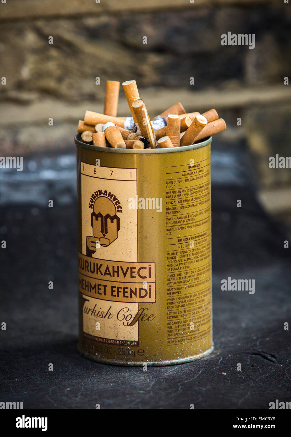 An old Turkish coffee container stuffed full of used cigarette ends. Stock Photo