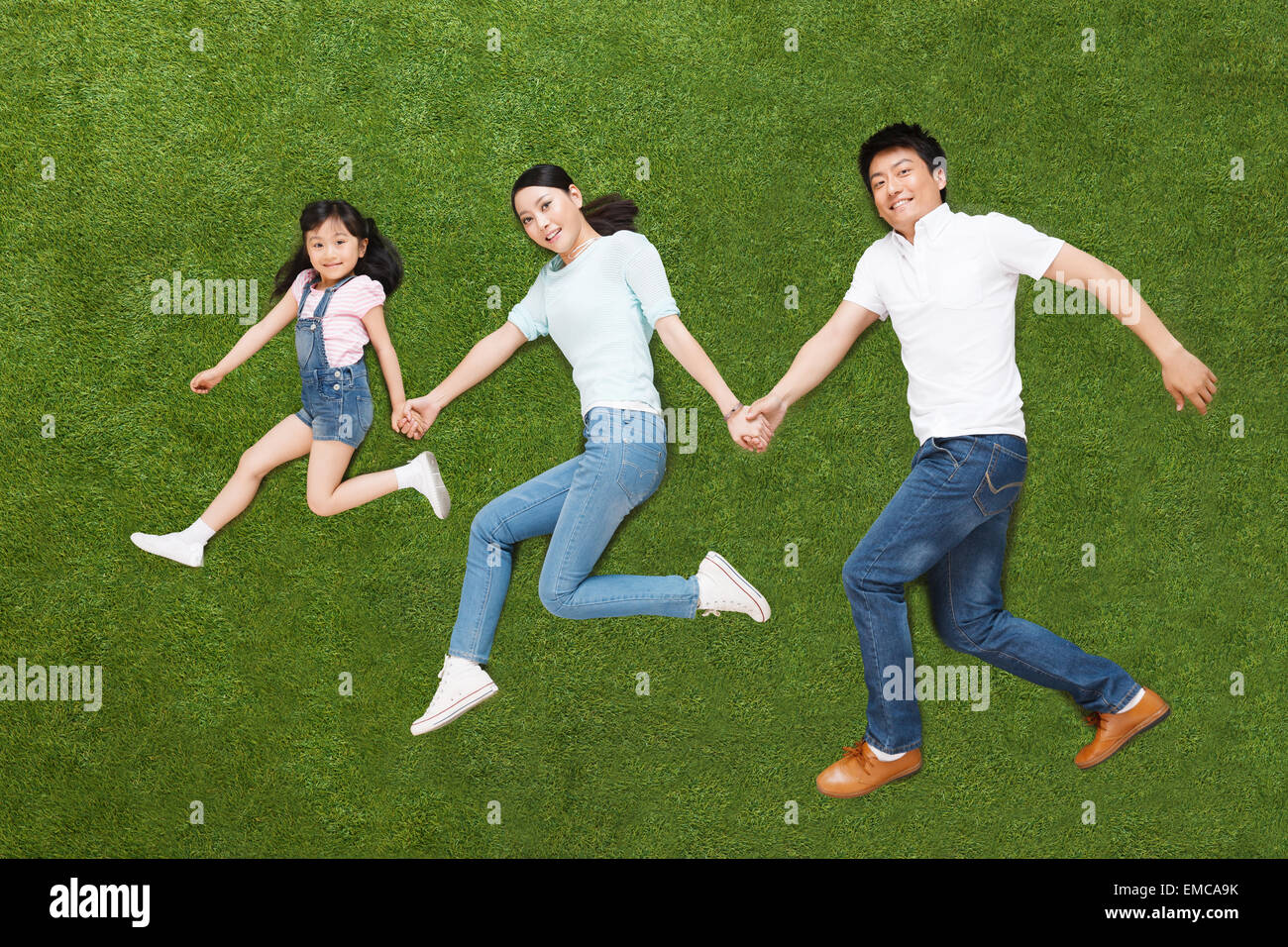 A family of three lying on the grass do running posture Stock Photo